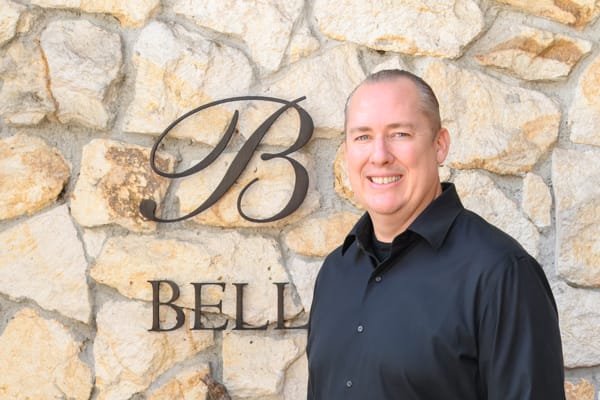 Scott Ayliffe, Director of Membership and Fulfillment at Bell Wine Cellars, smiling in front of the winery stone wall